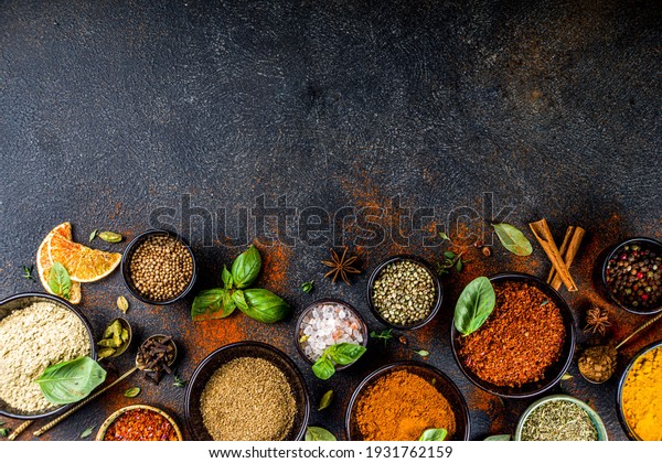 Set of\
Spices and herbs for cooking. Small bowls with colorful  seasonings\
and spices - basil, pepper, saffron, salt, paprika, turmeric. On\
black stone table top view copy\
space