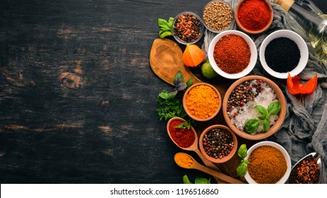 A set of spices and herbs. Indian cuisine. Pepper, salt, paprika, basil, turmeric. On a black wooden chalkboard. Top view. Free copy space. - Shutterstock ID 1196516860