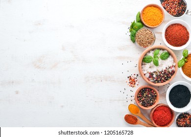 A set of Spices and herbs on a white wooden table. Basil, pepper, saffron, spices. Indian traditional cuisine. Top view. Free copy space.