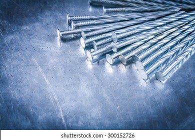 Set of stainless construction nails on scratched metallic background building concept.