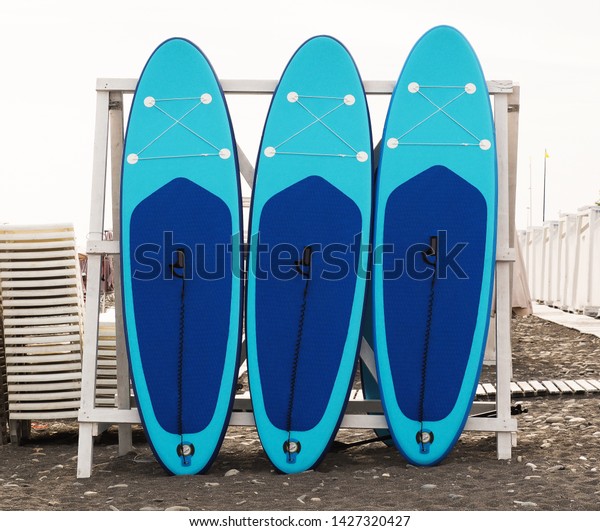 Set of stand-up paddleboard for SUP surfing in surf\
station on beach