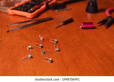 Set Of Steel Resistors Together With Vape Tools, On A Wooden Table.