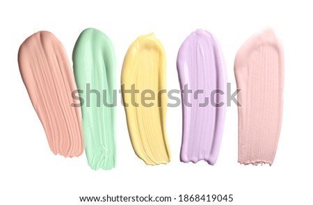 Set with strokes of color correcting concealers on white background, top view