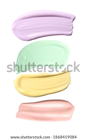 Set with strokes of color correcting concealers on white background, top view