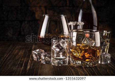 Set of strong alcohol drinks in glasses - whiskey, cognac, vodka, rum, tequila. Dark background.