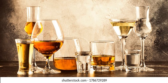 Set of strong alcoholic drinks in glasses in assortment: vodka, cognac, tequila, brandy and whiskey, grappa, liqueur, vermouth, tincture, rum. Panoramic banner with copy space