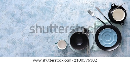 Set of stylish dinnerware on blue background with space for text