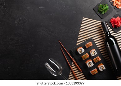 Set of sushi and maki with a bottle of wine on stone table. Top view with copy space.