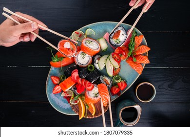 A set of sushi on a wooden table in a Japanese restaurant. sushi and sashimi on sticks, friends eat rolls in a Japanese restaurant top view Party of friends or family eating sushi