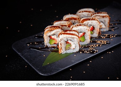 Set of sushi rolls dragon on a black matte plate.
Japanese traditional sushi dish with avocado, eel and soy sauce. A beautiful dish for an Asian restaurant menu. - Powered by Shutterstock