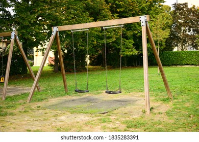 Set of swings on chains for little children in the local park with sand underneath and trees in the background. Park playground structure with swings. Lonely swing at summer day. - Powered by Shutterstock