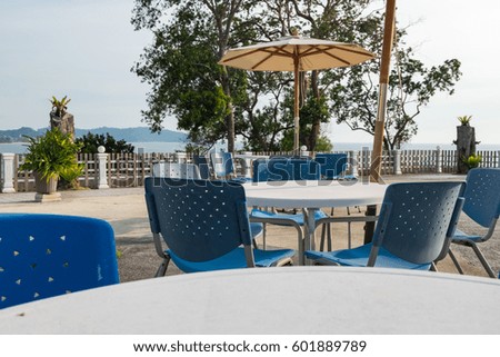 Set of table and chairs near the pool side with beautiful tropical sea scape background at day light