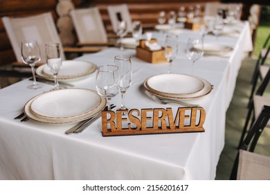 Set The Table On The Terrace With A Wooden Plate Reserved. Table Setting, Beautiful White Plates, Silver Cutlery And Crystal Glasses. Outdoor Feast On Holiday. Party