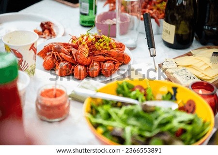 set table with a platter of boiled crayfish and various cheeses, salad and drinks all around