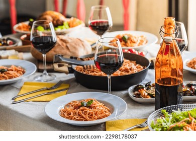 Set table of a restaurant with selective focus on a plate of spaghetti with tomato sauce. Bottle and glasses of red wine in the and organic food