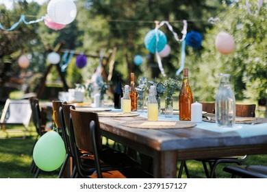 Set table for summer garden party. Table setting with glasses, fruit lemonade, fresh fruits and salads and delicate floral decoration. Colorful paper decorations for party. - Powered by Shutterstock