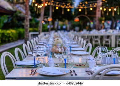 Set Table For A White And Aqua Blue Beach Wedding Dinner Decorated With Shells. Evening Time, Fairy Lights.