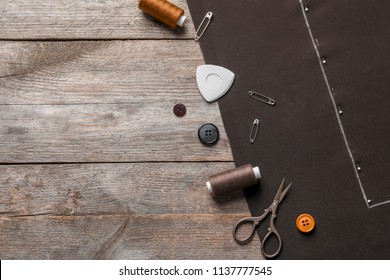 Set of tailoring accessories and fabric on wooden background, top view
