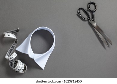 Set of tailoring tools and accessories on a gray background, top view. Tailor's scissors, measuring tape and blue shirt collar