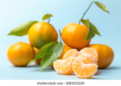 Set Of Tangerines, One Peeled In The Foreground, All Placed On A Blue Background