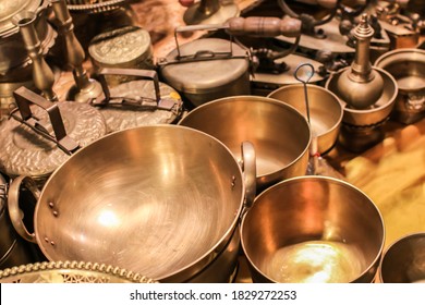 Set of thai traditional brass cookware that include a small and medium-sized saucepan, a large saucepan, pot, and cover stacked on top of the other, and a covered small pot.