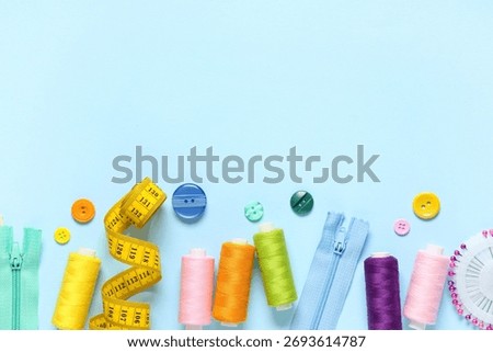 Set of thread spools with measuring tape and sewing supplies on blue background