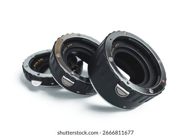 A set of three black and silver macro extension tubes for a camera, isolated on a clean white background.
