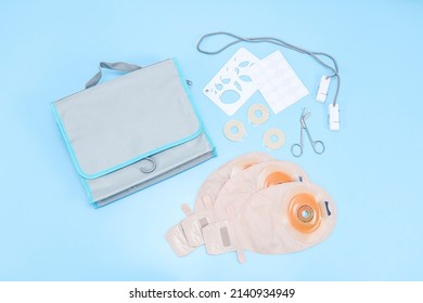 A set of three colostomy bags with medical scissors, a stencil of different diameters, a sticky circle, a bag and clothespins on a rope lie on a gentle blue background, flat lay . Colon cancer concept