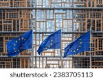 set of three flags of the European Union waving in the wind in front of the EU Council building façade in Brussels. Exterior Europa building. Restored window frames facade. union concept 