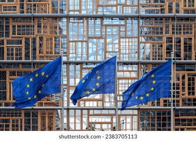 set of three flags of the European Union waving in the wind in front of the EU Council building façade in Brussels. Exterior Europa building. Restored window frames facade. union concept 