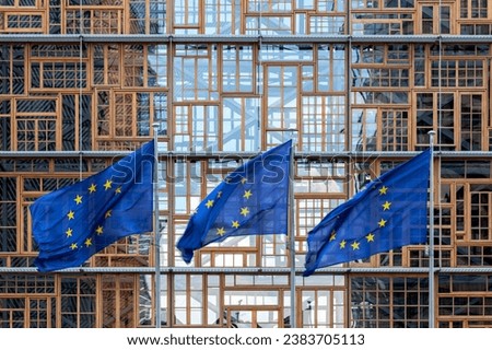 set of three flags of the European Union waving in the wind in front of the EU Council building façade in Brussels. Exterior Europa building. Restored window frames facade. union concept 