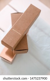 Set Of Three Long Package Boxes In Brown Craft And Rose Gold Color Paper. Overhead, On White. Beauty, Fashion Blogging, Minimalism Concept