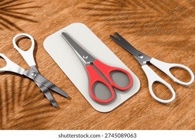 A set of three pairs of scissors with different handle designs on a wooden surface