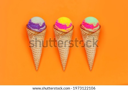 Set of three types of sweet multicolored sorbet ice-cream in a waffle cones with different fruit and berry flavors isolated on a color bright orange background. Summer concept