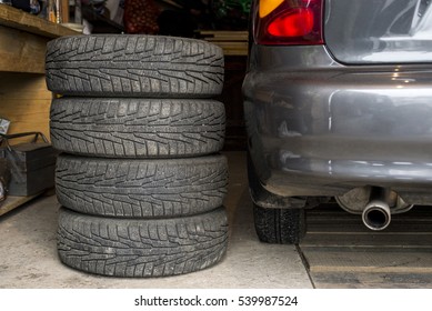 Set Of Tires And The Car In The Garage. Replacement Tires. Tire