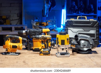 A set of tools and electrical devices is on the table. circular saw, screwdriver, perforator, drill, jigsaw, router in a carpentry workshop