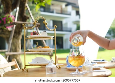 A Set Of Traditional Afternoon Tea, Comprises Of Sweet, Savory Delicacies And Scone. Blurred Background With A Woman Hand Pouring A Tea.