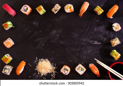 Set of traditional japanese food on a dark background. Sushi rolls, nigiri, raw salmon steak, rice, cream cheese, avocado, lime, pickled ginger. Asian food frame. Dinner party. 



