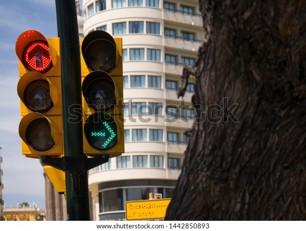 A set of traffic lights has a red stop sign for\
vehicles going straight ahead and a green go arrow for cars turning\
right - Image