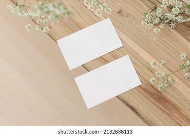 Set of two blank business cards and cow parsley flowers. Old wooden table. Flat lay, top view, selective focus, blurred background. Feminine stationery. Wedding, birthday desktop mock-up scene. 