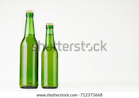 Set of two green longneck beer bottles 330ml, mock up. Template for advertising, design, branding identity on white wood table.