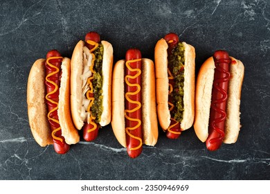 Set of unique hot dogs with a variety of toppings. Above view on a dark stone background. - Powered by Shutterstock