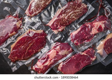 Set of vacuum packed organic raw beef alternative cuts: top blade, rump, picanha, chuck roll steaks, over black textured background, top view