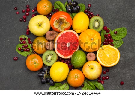 Set of varied, multicolored exotic fruits. Tangerines and oranges, kiwi and pear, persimmon and lychee. Black Background. Flat lay
