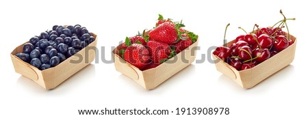 Set of various berries - blueberry, cherry and strawberry in wooden container box, isolated on white background