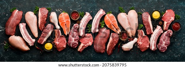 Set of various classic, alternative raw meat,\
veal beef steaks, pork, chicken fillet, fish, salmon steak. Top\
view. On a black stone\
background.