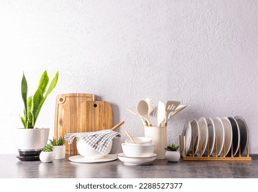 a set of various kitchen utensils and tools, ceramic dishes in light colors on a modern kitchen countertop. front view. a copy space