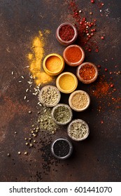 Set of various multicolored spices in jars over dark brown concrete background. Assorted condiment. Top view, close up, flat lay. Food background