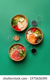 Set of various poke in cardboard bowls with sauces over green background. Poke with tuna, salmon or chicken. Top view, flat lay, copy space. Traditional Hawaiian dish