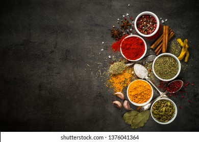 Set of various spices on black background. Pepper, turmelic, paprika, basil, rosemary, chilly, cardamom, cinnamon, anise. Top view with copy space.